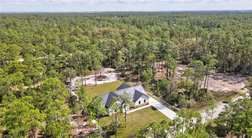 Aerial view of property and surrounding area featuring a forest