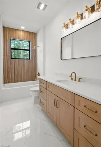 Bathroom with vanity, shower / bathtub combination, light marble finish flooring, and recessed lighting