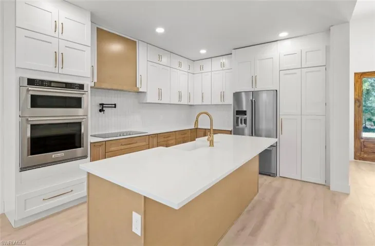 Kitchen featuring stainless steel appliances, white cabinets, decorative backsplash, recessed lighting, and light wood-style flooring