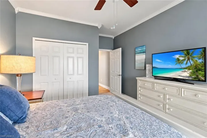 Tray ceiling with crown molding, ceiling fan with light fixture, bi-fold closet doors, and wood-finish flooring - Virtually Edited Image