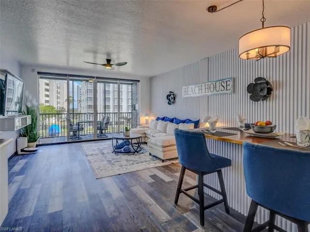VIEW OF DINING/LIVING AREA TOWARDS LANAI.  FLUTED WOOD ACCENT WALL.  WOOD-LOOK VINYL PLANK FLOORING THROUGHOUT.  CUSTOM INTEGRATED DINING ISLAND.