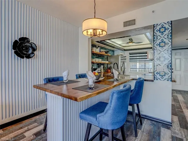 CUSTOM INTEGRATED DINING ISLAND W/ACACIA WOOD TOP AND FLUTED WOOD ACCENT BASE.  ENTRANCE TO UNIT IS SHOWN AT REAR RIGHT.
