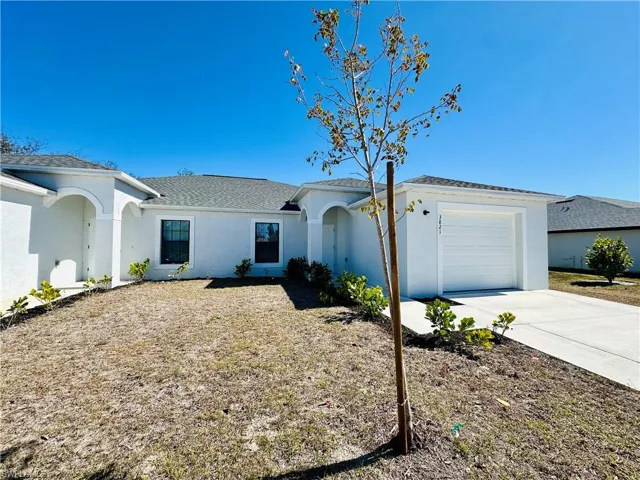 Ranch-style home with roof with shingles, stucco siding, an attached garage, and driveway