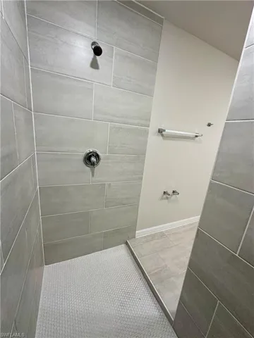 Bathroom with tiled shower and light tile patterned flooring