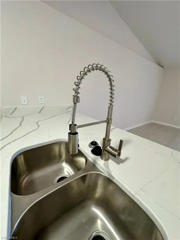 Kitchen view of light stone counters and a sink