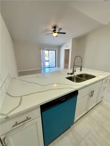 Kitchen featuring white cabinetry, open floor plan, dishwashing machine, wood finish floors, and vaulted ceiling