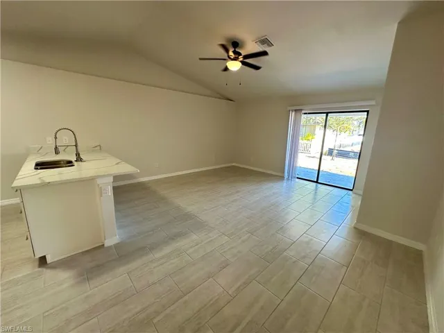 Unfurnished living room featuring vaulted ceiling, wood tiled floors, and ceiling fan