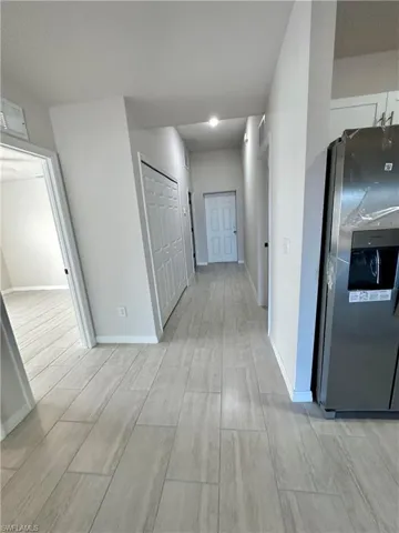 Corridor with light wood-type flooring and baseboards