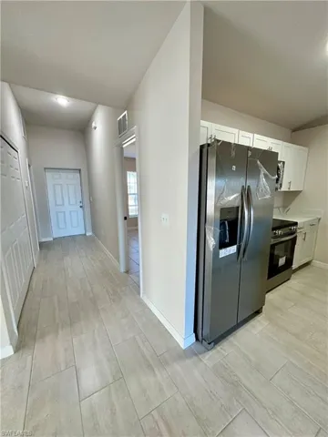 Kitchen with stainless steel appliances, wood tiled floors, white cabinets, and light countertops