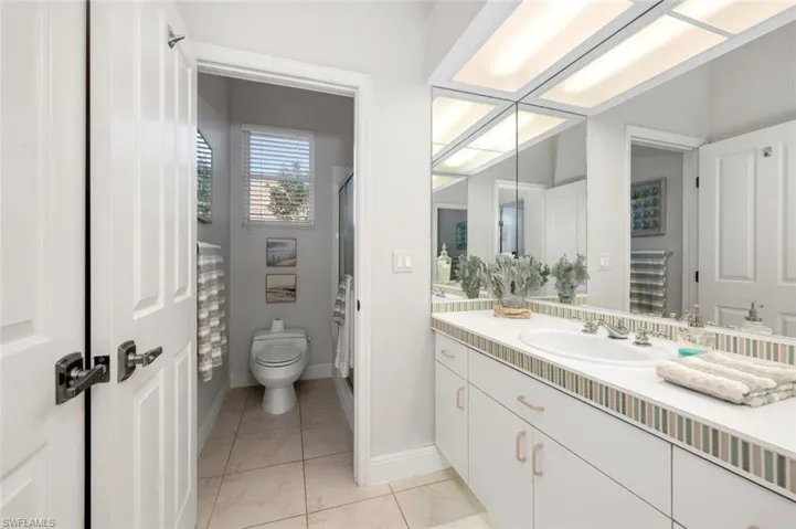 Bathroom featuring toilet, tile patterned flooring, a shower, and vanity