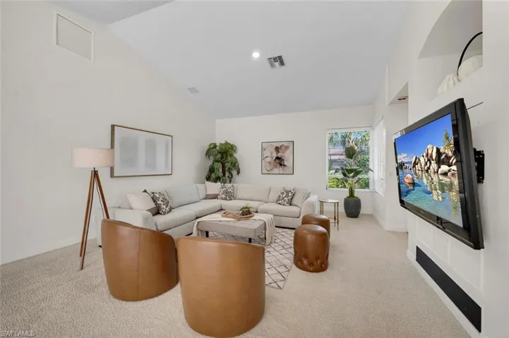 Carpeted living room featuring vaulted ceiling