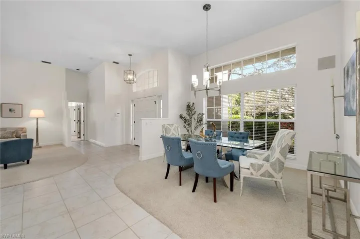 Dining room with light tile patterned floors, a towering ceiling, and an inviting chandelier