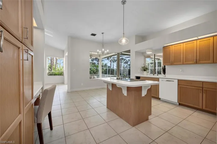 Kitchen featuring a kitchen bar, a notable chandelier, white dishwasher, hanging light fixtures, and a center island