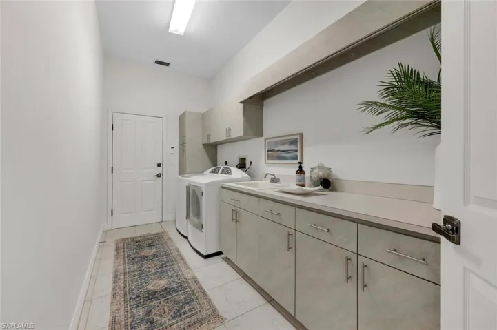 Washroom featuring cabinets, sink, washing machine and dryer, and light tile patterned flooring