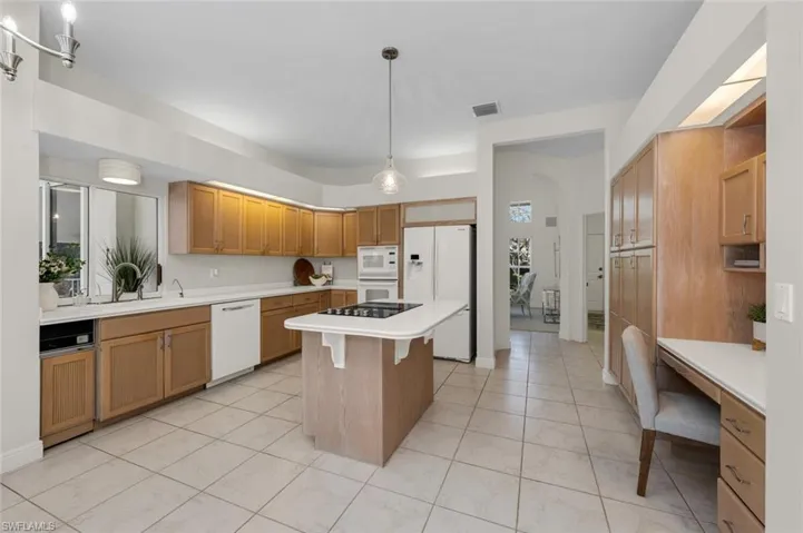 Kitchen featuring a kitchen island, light tile patterned flooring, sink, white appliances, and hanging light fixtures