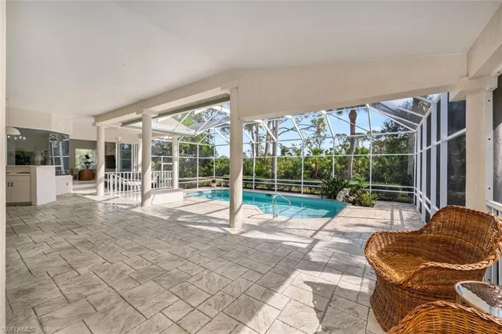 View of pool featuring glass enclosure and a patio