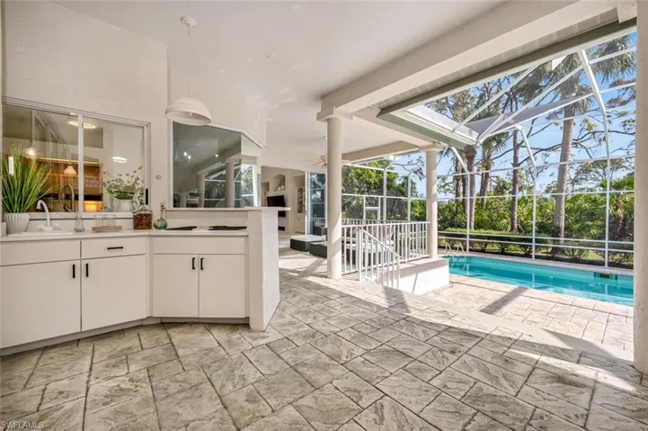 View of swimming pool featuring a patio area, sink, and glass enclosure