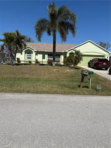 Ranch-style home with a garage, concrete driveway, a front yard, and a shingled roof