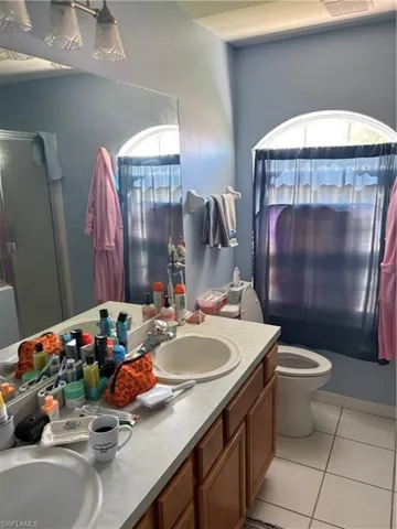 Bathroom with double vanity, light tile patterned flooring, and shower / bath combo