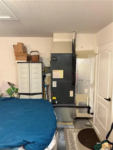 Bedroom with concrete flooring, a textured ceiling, and heating unit