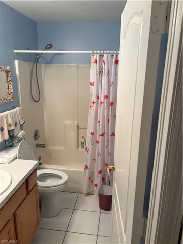 Full bathroom with vanity, shower / bath combination with curtain, light tile patterned flooring, and a textured ceiling