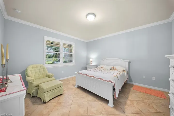 Tile flooring, a window with horizontal blinds, and crown molding