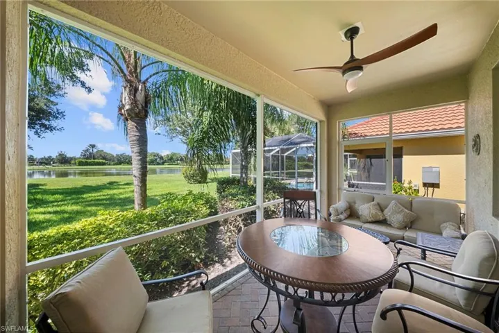 Screened lanai featuring a ceiling fan, a tiled floor, and views of a body of water with lush landscaping