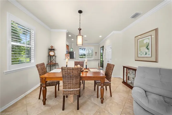 Crown molding accents a room with tiled flooring and a pendant light fixture