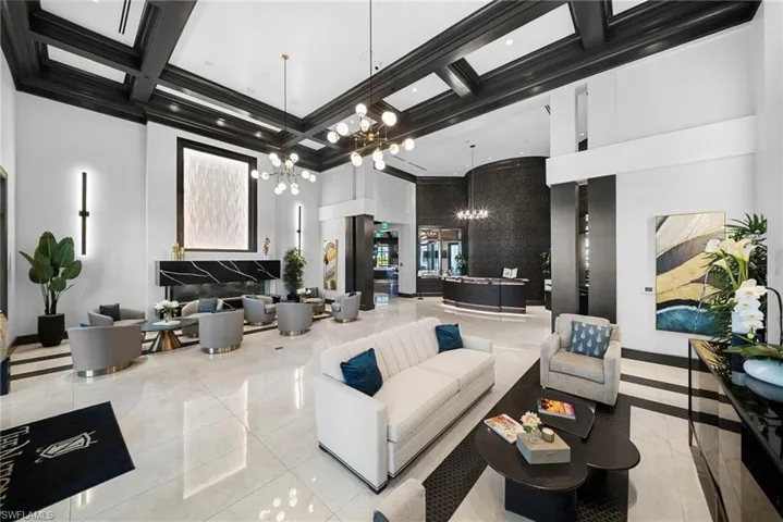 Spacious communal area featuring coffered ceilings, large format tile flooring, a built-in fireplace with a stone surround, and integrated wall lighting