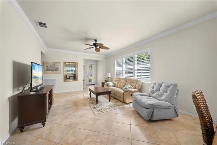 Tiled flooring, crown molding, ceiling fan, and white window shutters