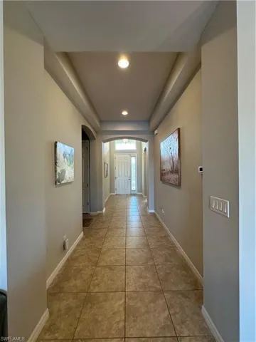 Corridor flowing from open Living Area towards front door with hallway on left leading to Den, Laundry Room and Garage. Foyer on right leading to Bedrooms #2 and #3, separated by Full Bathroom.