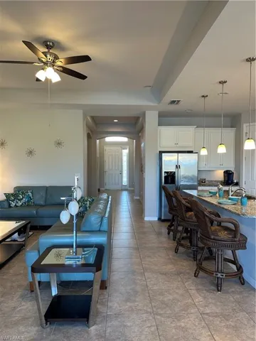 Living room featuring sink, light tile patterned floors, and ceiling fan