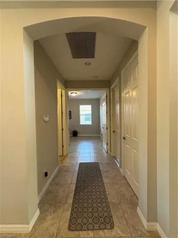 Hallway leading straight to Den w/ Double 8' doors; laundry room to the left and door leading to garage to the right.