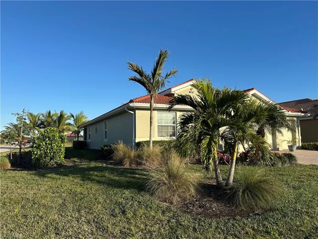 View of left side of home featuring tropical landscaping