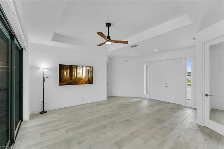 Empty room with light hardwood / wood-style floors, a raised ceiling, and ceiling fan