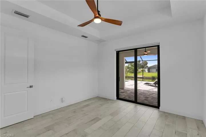 Unfurnished room featuring light hardwood / wood-style floors, ceiling fan, and a tray ceiling