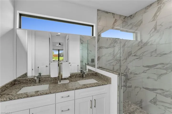 Bathroom with an enclosed shower, ceiling fan, and dual bowl vanity