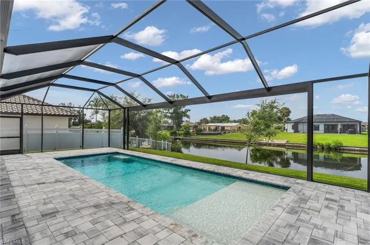 View of swimming pool featuring a patio, a water view, and a lanai