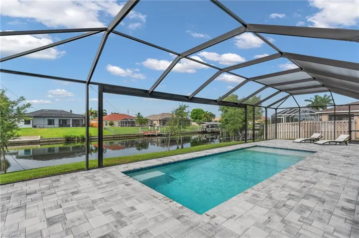 View of swimming pool featuring a patio area, a yard, glass enclosure, and a water view