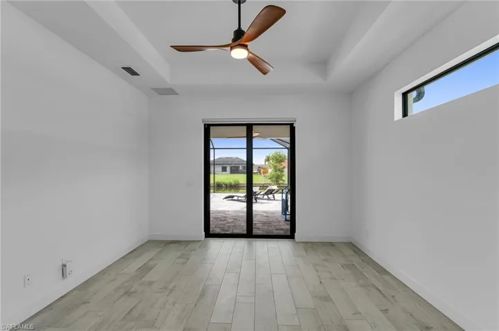 Empty room with a healthy amount of sunlight, ceiling fan, and a raised ceiling