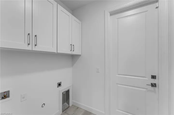 Washroom featuring hookup for a washing machine, cabinets, light hardwood / wood-style flooring, and hookup for an electric dryer