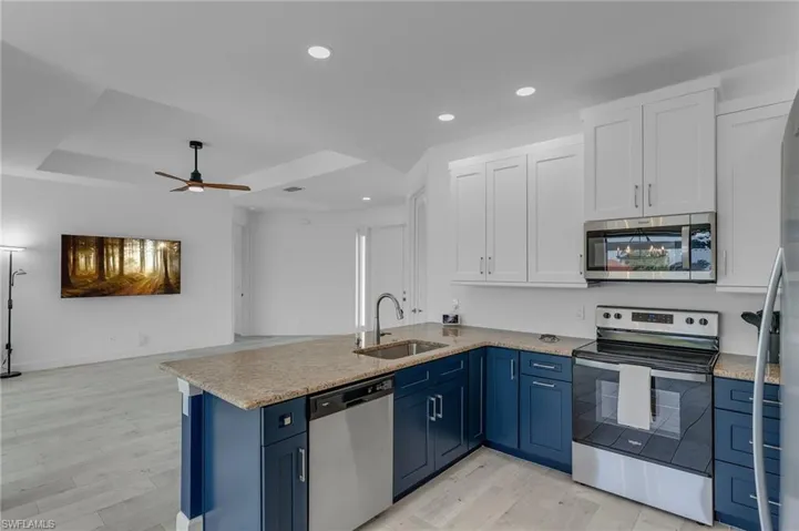 Kitchen with sink, appliances with stainless steel finishes, ceiling fan, and blue cabinetry