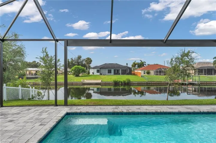 View of swimming pool with glass enclosure, a water view, and a lawn
