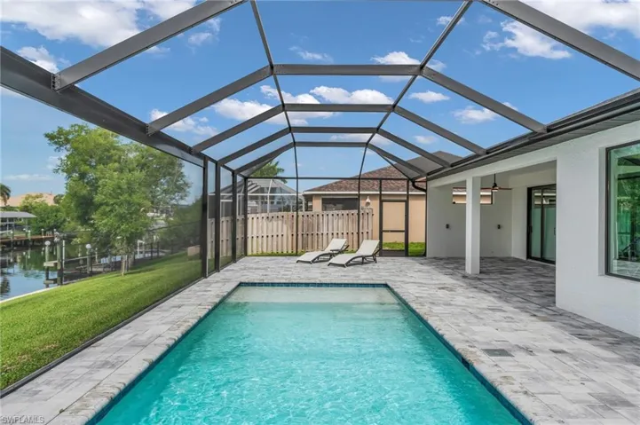 View of pool featuring a patio, ceiling fan, glass enclosure, and a lawn