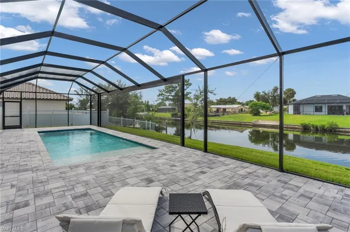 View of swimming pool with a water view, a yard, a patio area, and a lanai