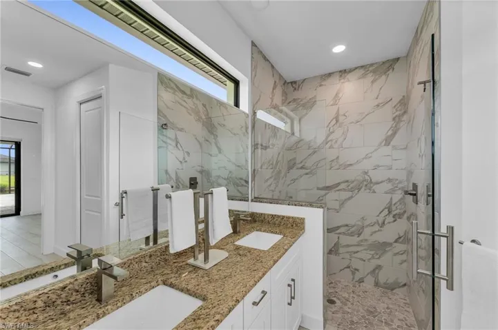 Bathroom with walk in shower, a healthy amount of sunlight, and double sink vanity