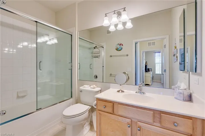 Bathroom with vanity, combined bath / shower with glass door, light tile patterned floors, and a chandelier