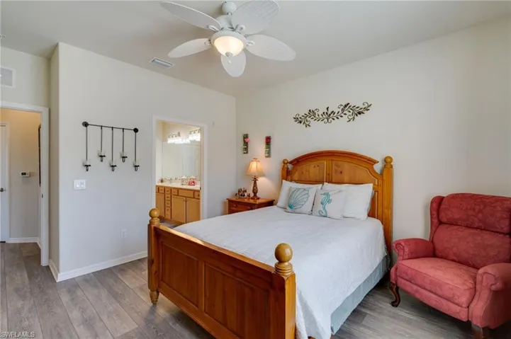 Bedroom featuring wood finished floors, a ceiling fan, and ensuite bathroom
