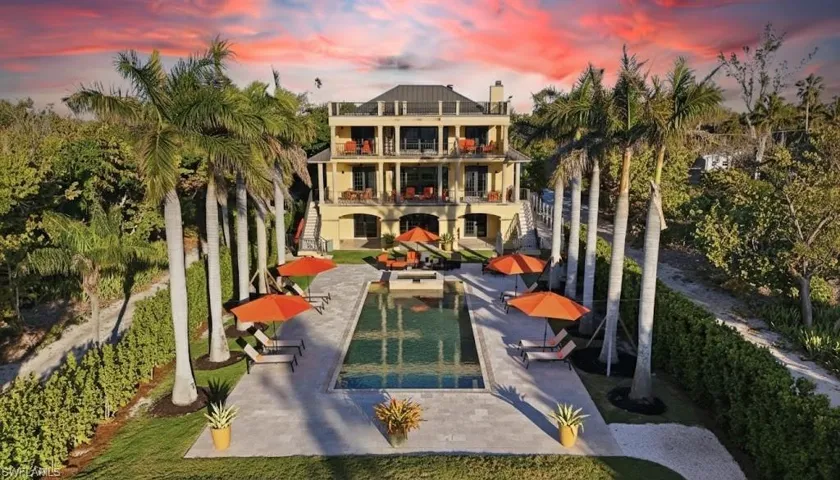 Back of property featuring a balcony, a patio area, and a swimming pool