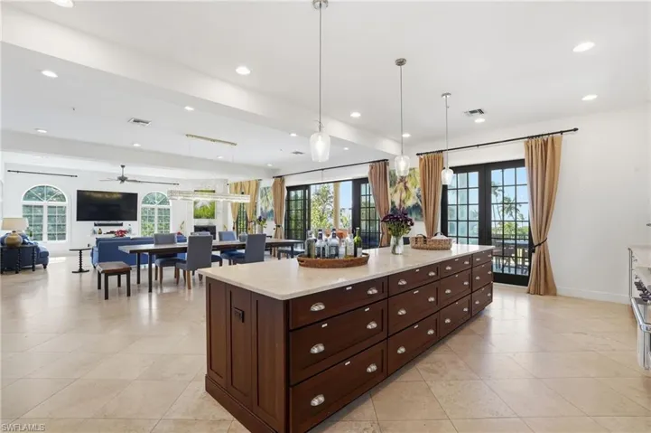 Kitchen featuring open floor plan, dark wood finish cabinets, decorative light fixtures, french doors, and light stone counters